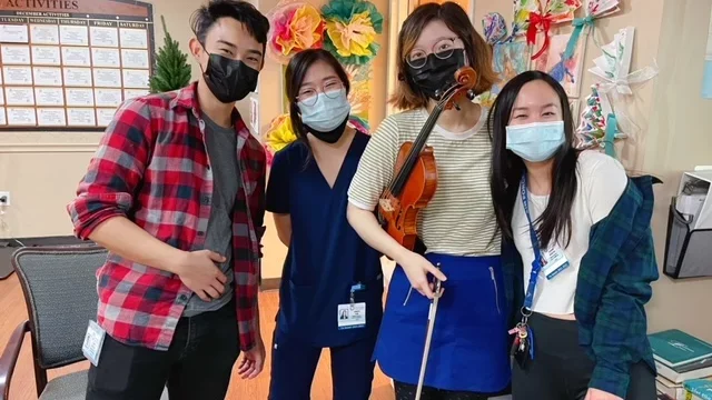 A group of medical students with string instruments in a medical facility