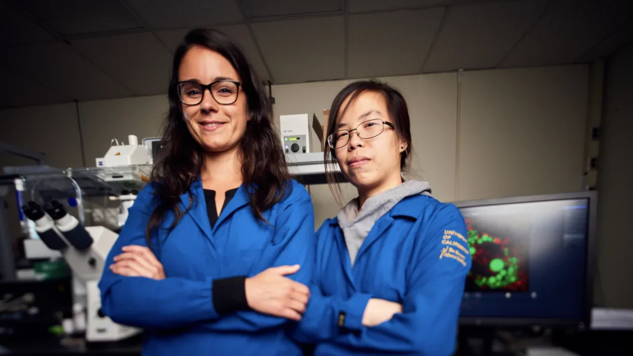 Research trainees posing in front of a high powered microscope