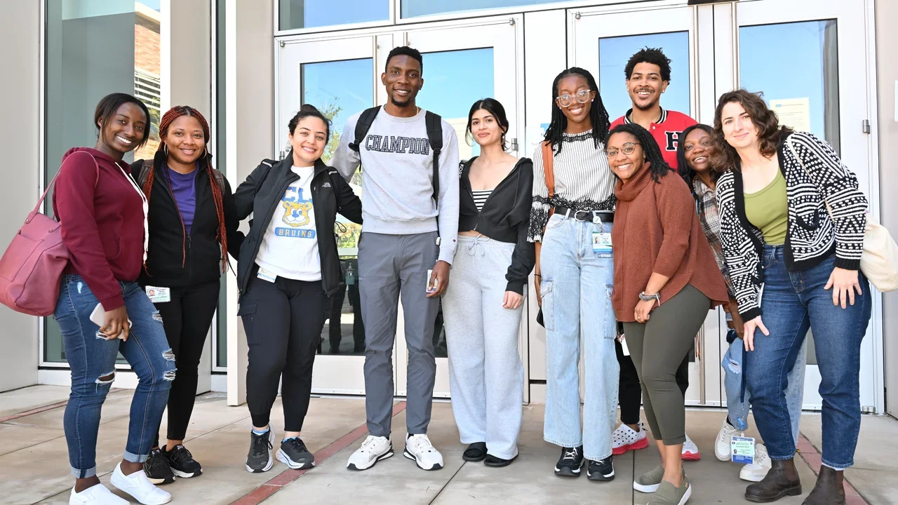 Students gather outside a building, posing together for a group photo, capturing a moment of friendship and unity.