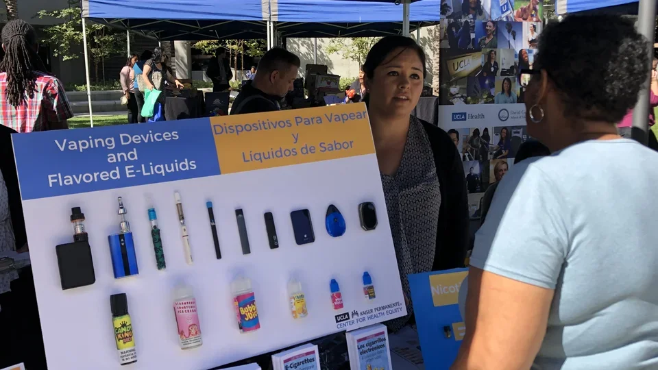 How to Prevent Cancer Via Lifestyle Choices. People review information on vaping at a health fair