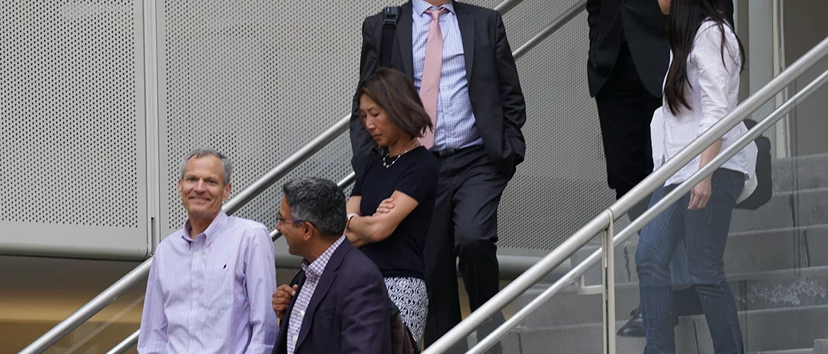 A group of faculty presenting on Immunology chatting on the stairs in the courtyard of Geffen Hall