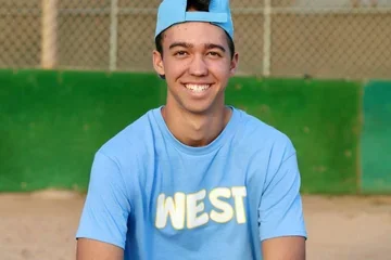 A young black man in casual sports attire smiling at the camera.