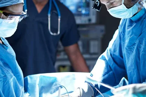 Photo of three medical professionals performing surgery 