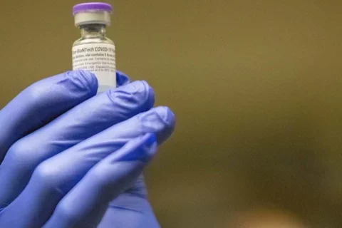 gloved hand holding vaccine