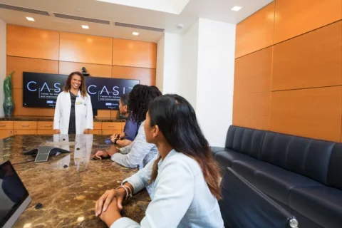 A woman is addressing an audience in a conference room, showcasing her ideas during a professional presentation.