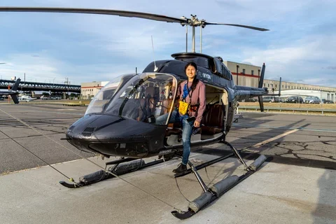 Xin Qi posting in front of a helicopter