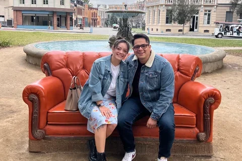 Darwin and Jennifer Gutierrez, DGSOM alumni who fell in loving during medical school, posing on an orange couch 