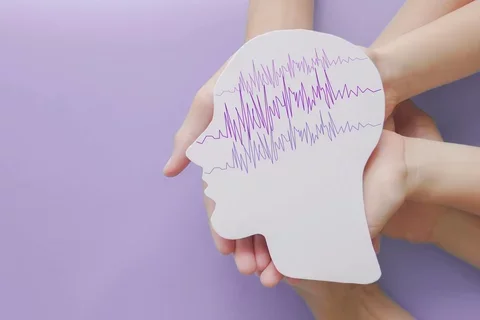 hands holding cut out of head shaped paper