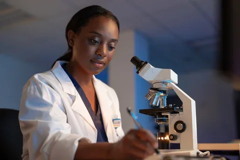 Woman writing notes with microscope