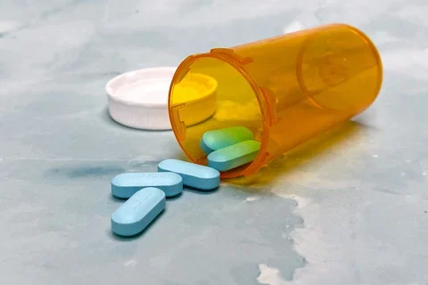 Blue pills spilling out of pill bottle