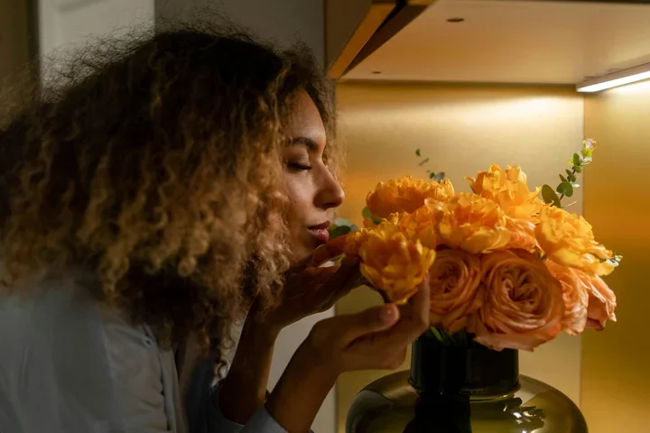 Woman smelling an orange bouquet of flowers