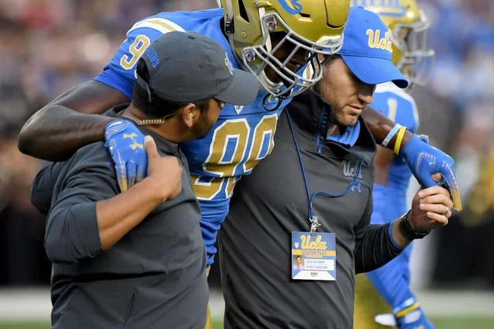 Sports medicine professionals helping an injured UCLA football player off the field 