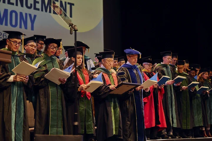 : Award-winners Jessica B. O'Connell, MD (front row, third from the left) and Kat-Kit Hui, MD (front row, fourth from the left) join graduating doctors in reciting the Oath of Hippocrates at the 2026 commencement ceremony.