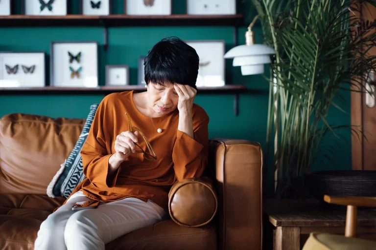 Woman sitting on couch and holding head