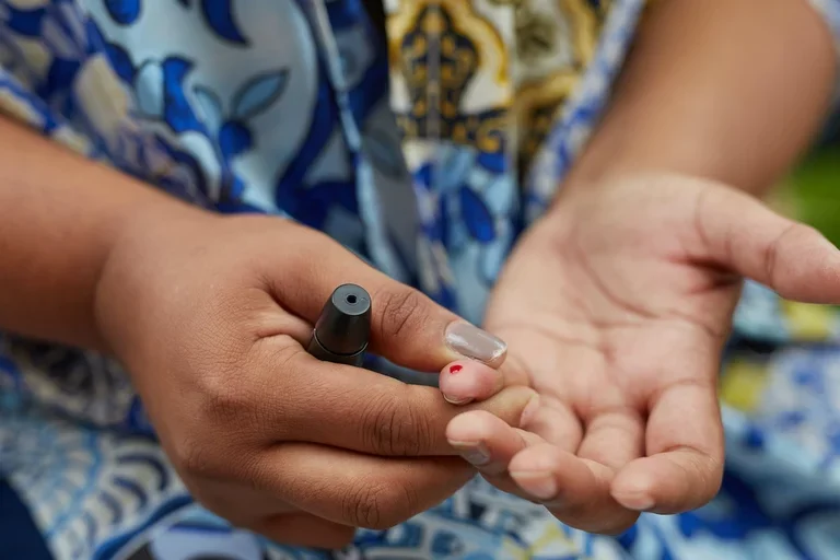Can diabetes be reversed? Woman doing a blood sugar finger prick test. 