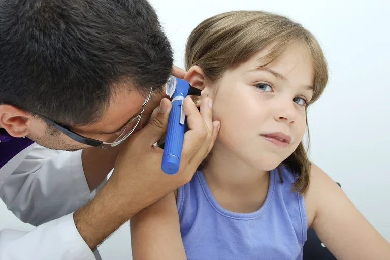 Otolaryngologist making a revision to a girl with an otoscope. 