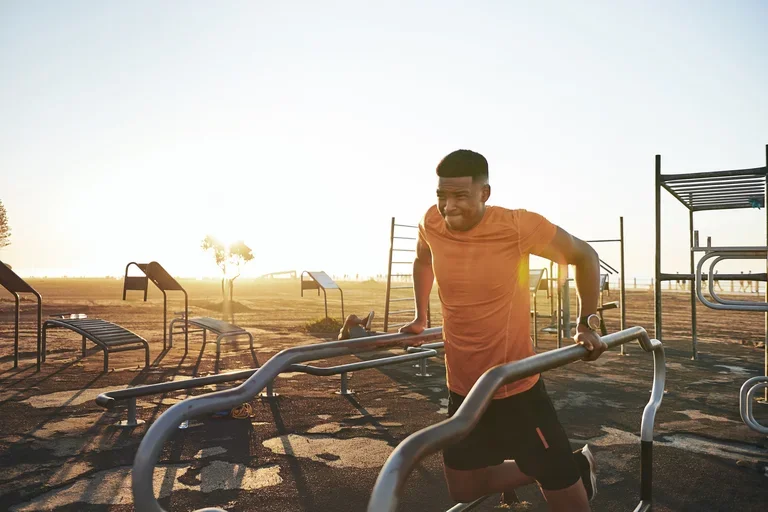 A man working out at an outdoor park in the sun