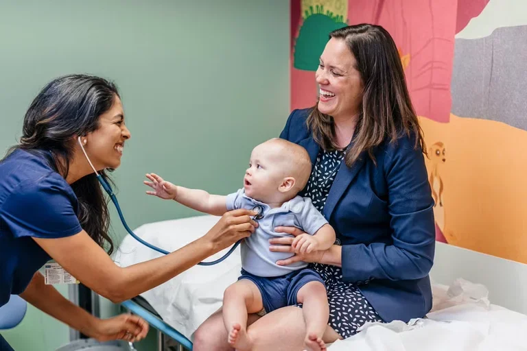 A clinician uses a stethoscope on an infant