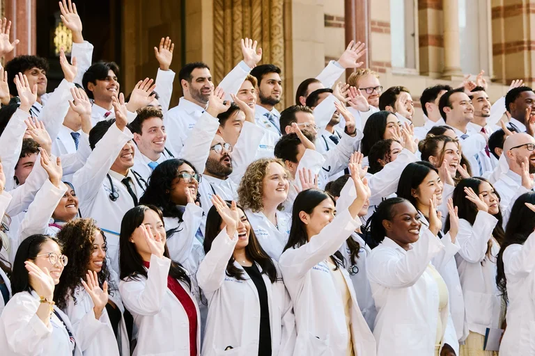 DGSOM’s class of 2030 waving and smiling candidly in front of UCLA’s Royce Hall.
