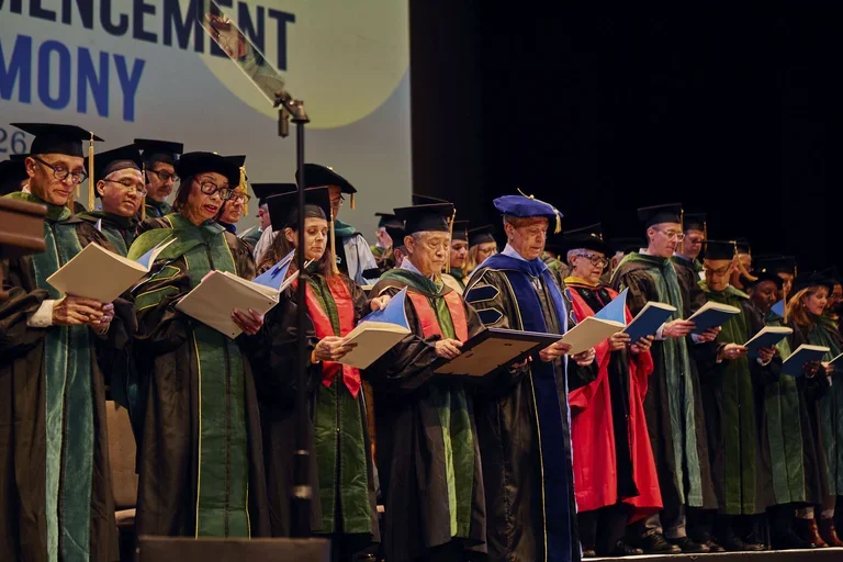 : Award-winners Jessica B. O'Connell, MD (front row, third from the left) and Kat-Kit Hui, MD (front row, fourth from the left) join graduating doctors in reciting the Oath of Hippocrates at the 2026 commencement ceremony.