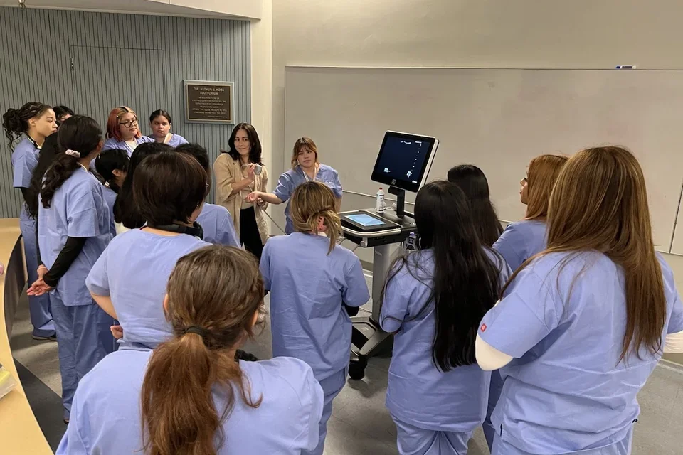 A group of medical students wearing scrubs complete a hands-on training exercise