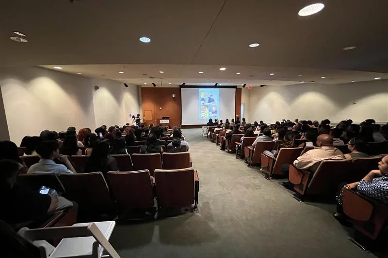 A group of people watch a presentation in an auditorium 