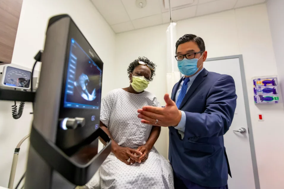 A hospital administrator discussing records with a patient, both wearing masks