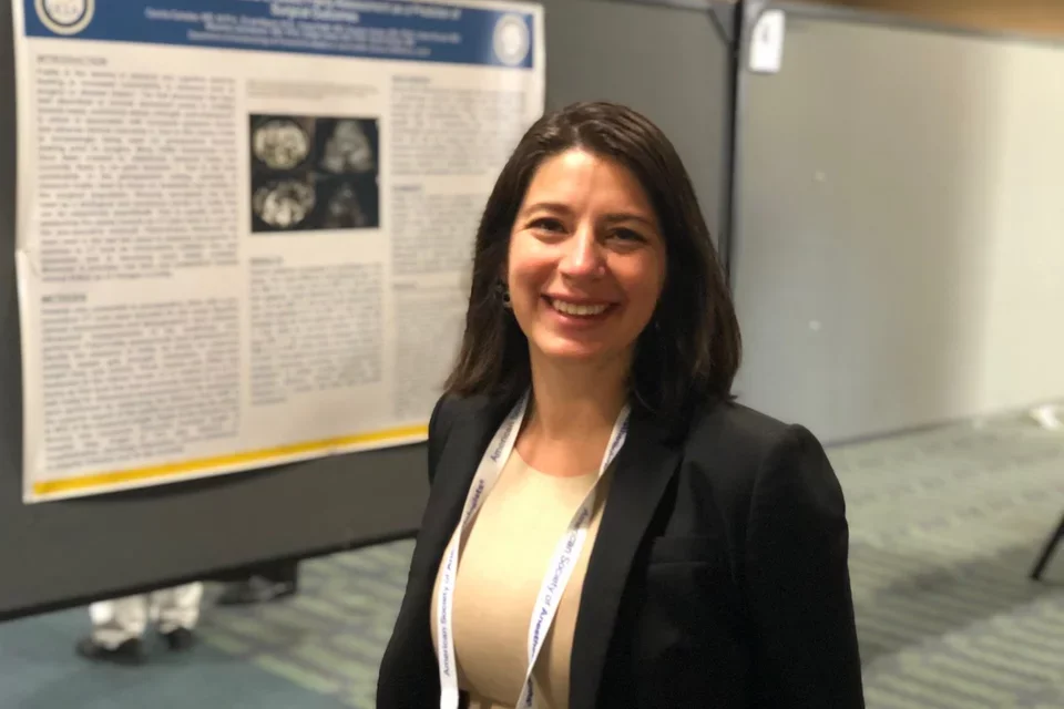 UCLA's Dr. Cecilia Canales, pictured smiling at a poster presentation, shares her expertise about anesthesia side effects. 