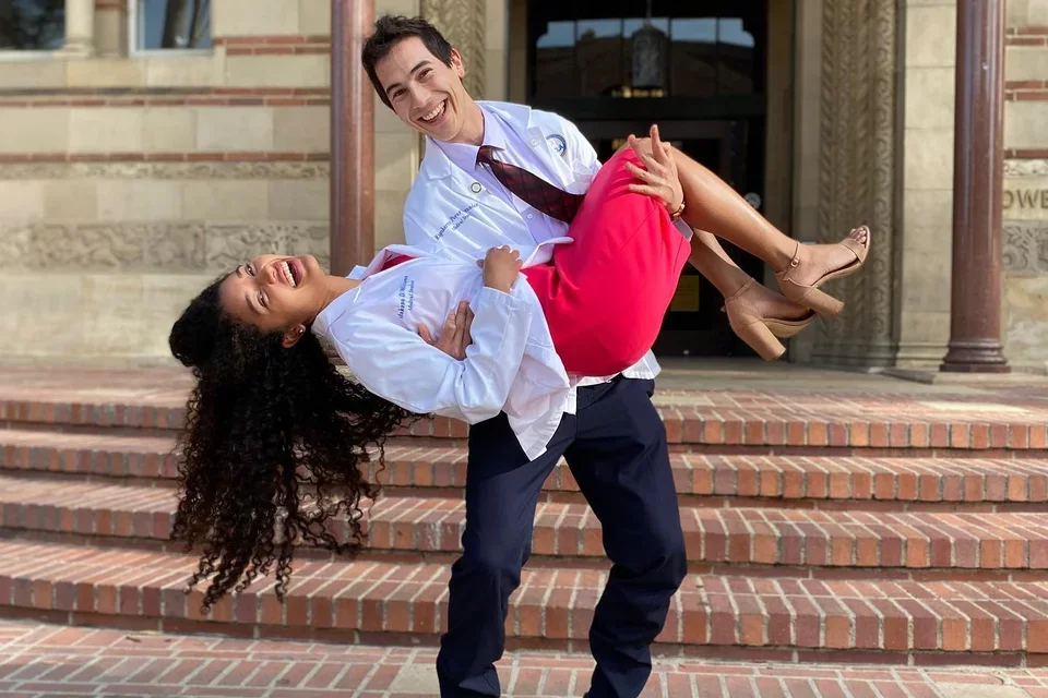 UCLA residents and med-school alumni Makana Williams and Rigoberto Perez Hernandez posing in their White Coats in front of the UCLA library. 