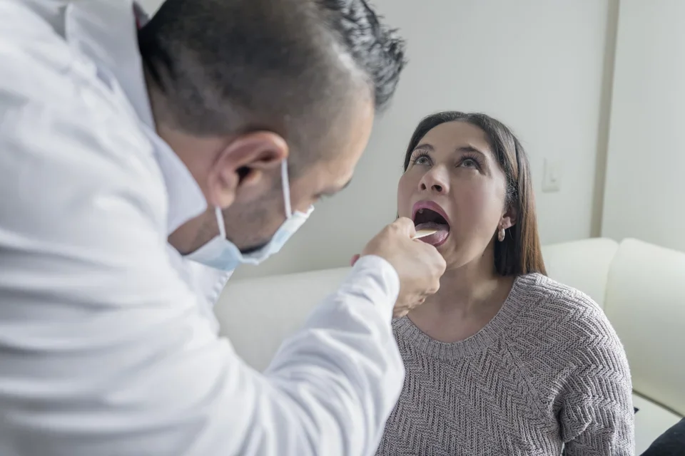 ENT doctor evaluating a patient’s throat for otolaryngology-related conditions