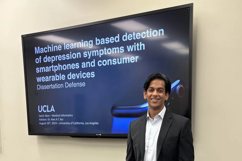 UCLA’s first medical informatics PhD, Samir Akre, pictured here standing in front of the title screen for his dissertation defense. 