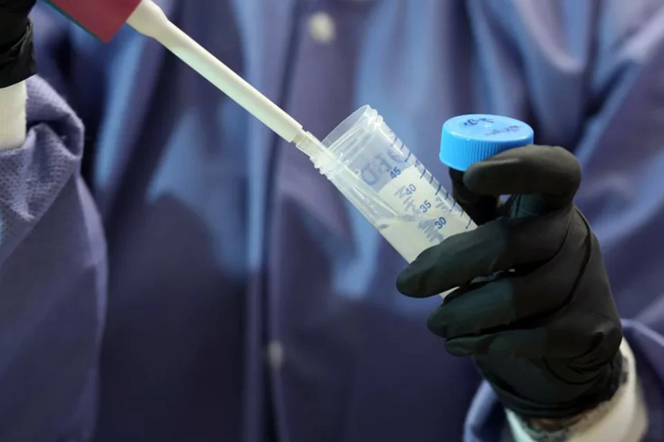 Person in a lab wearing gloves and holding a test tube