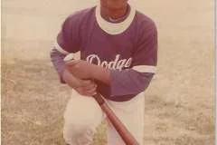 Dr. Langston as a child kneeling on one knee with a baseball bat