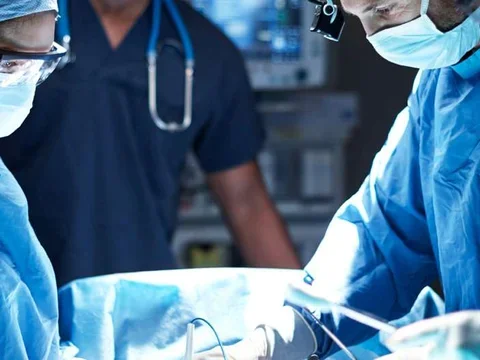 Photo of three medical professionals performing surgery 