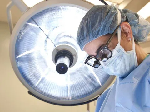 Photo of Doctor in surgery with surgical lamp behind them 