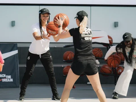Two women passing basketball to each other