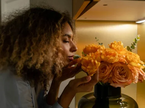 Woman smelling an orange bouquet of flowers