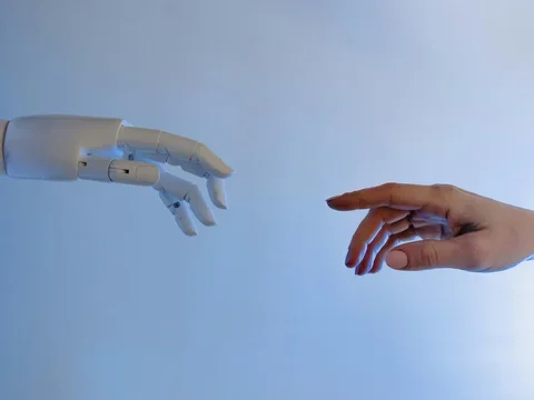 Robotic hand almost touching a human hand