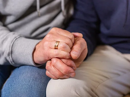 Spouse holding hands resting on legs