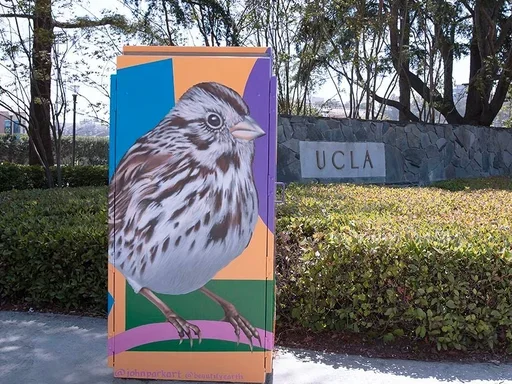 Utility box with bird mural in front of UCLA sign