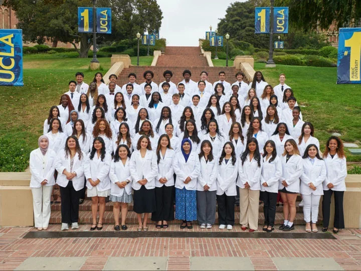The 2025 cohort of SHPEP Scholars standing in their white coats on UCLA Janss Steps