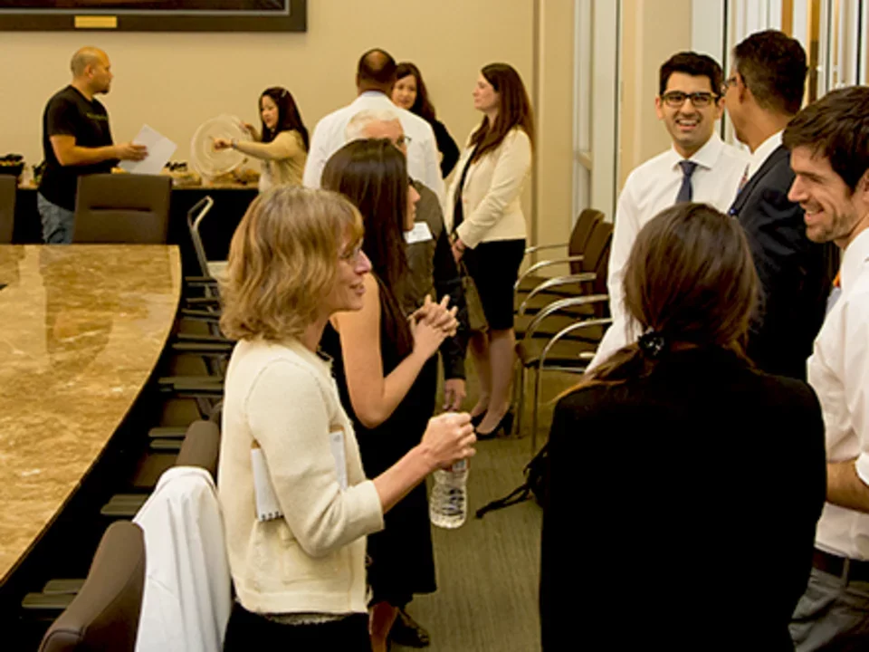 Several groups of people having conversations in a conference room.