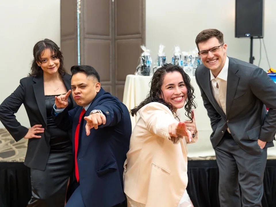 Darwin and Jennifer Gutierrez, DGSOM alumni who fell in loving during medical school, posing with classmates at a formal  