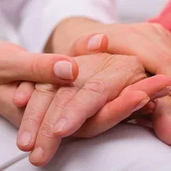 Alzheimer's Vs Dementia Closeup of Younger Caregiver Gently Holding Hands With a Senior Patient