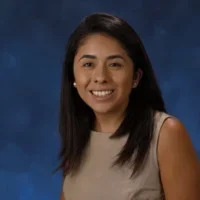 Andrea Martinez smiling portrait in front of blue backdrop