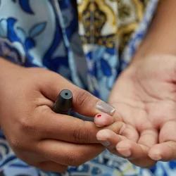 Can diabetes be reversed? Woman doing a blood sugar finger prick test. 