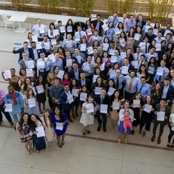 Medical Students matching stand in a courtyard together holding their match letters up with big smiles.