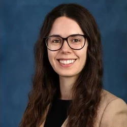 Molly Hemphill smiling portrait in front of blue backdrop