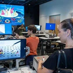 Catherine Nameth, the medical school's director of faculty professional development, tests surgical skills using suturing and laparoscopic box trainers at Rosenfeld Hall opening event. Photo: Reed Hutchinson