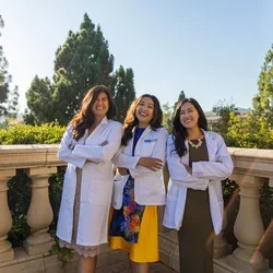 Medical student Clara Đỗ Trần Nguyễn, pictured in her white coat along with her two physician sisters, shares her story of becoming a doctor 